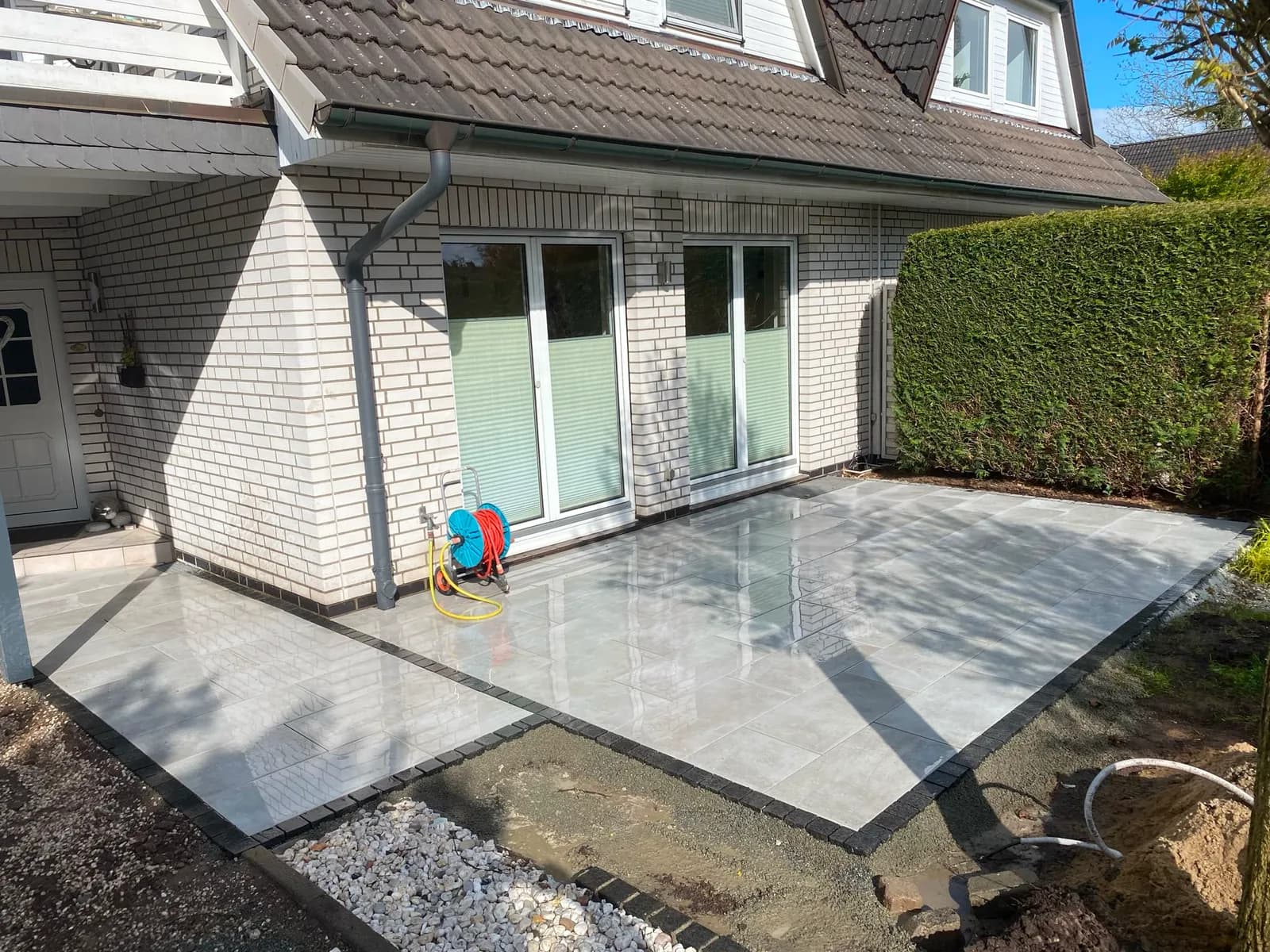 Fertig verlegte Terrasse aus großformatigen Feinsteinzeugplatten mit Pflaster-Randeinfassung am Wohnhaus in Elmshorn